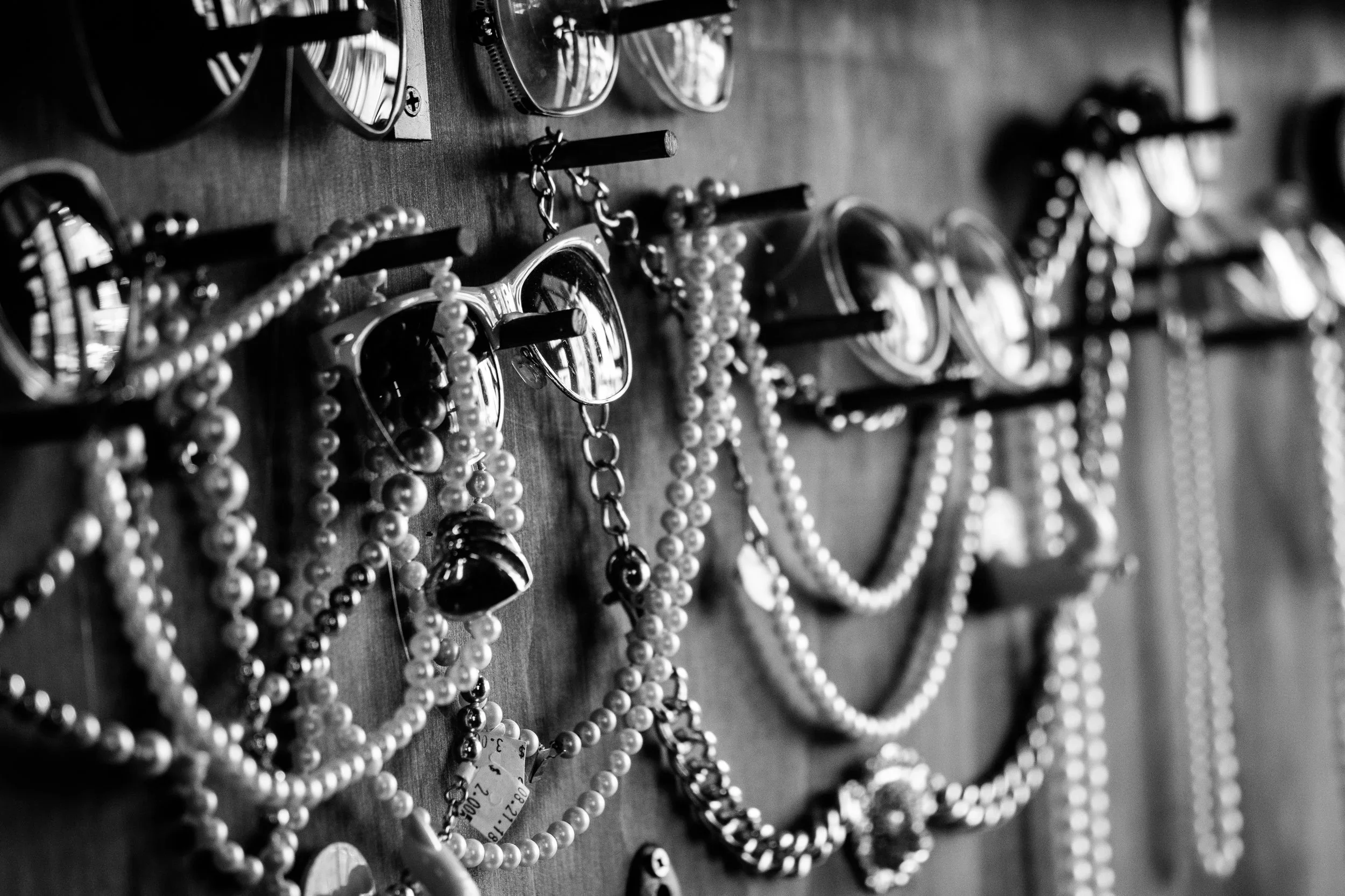 Black and white photo of jewelry, including necklaces, bracelets, and earrings, displayed on a wooden board.