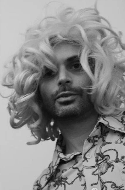 Damien Chabaud-Arnault co-founder of The Pawn Shop  with long, curly blonde hair wearing a patterned shirt with snakes and other creatures.