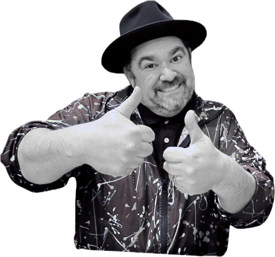 Michael Anthony Levitt who is part of the team at The Pawn Shop wearing a black hat and a black jacket with white paint splatter design, smiling and giving two thumbs up.