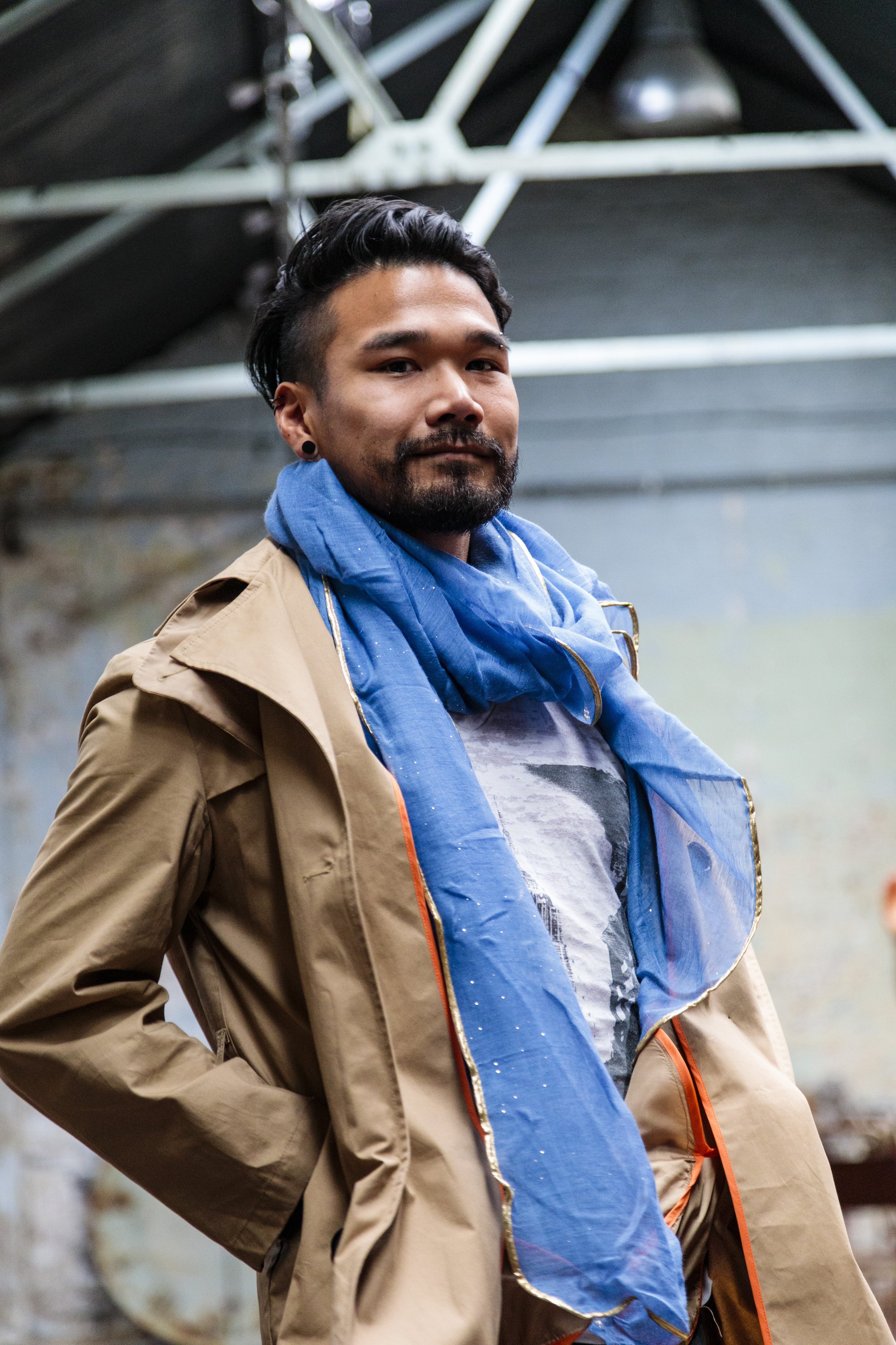 Man in a beige jacket and blue scarf indoors