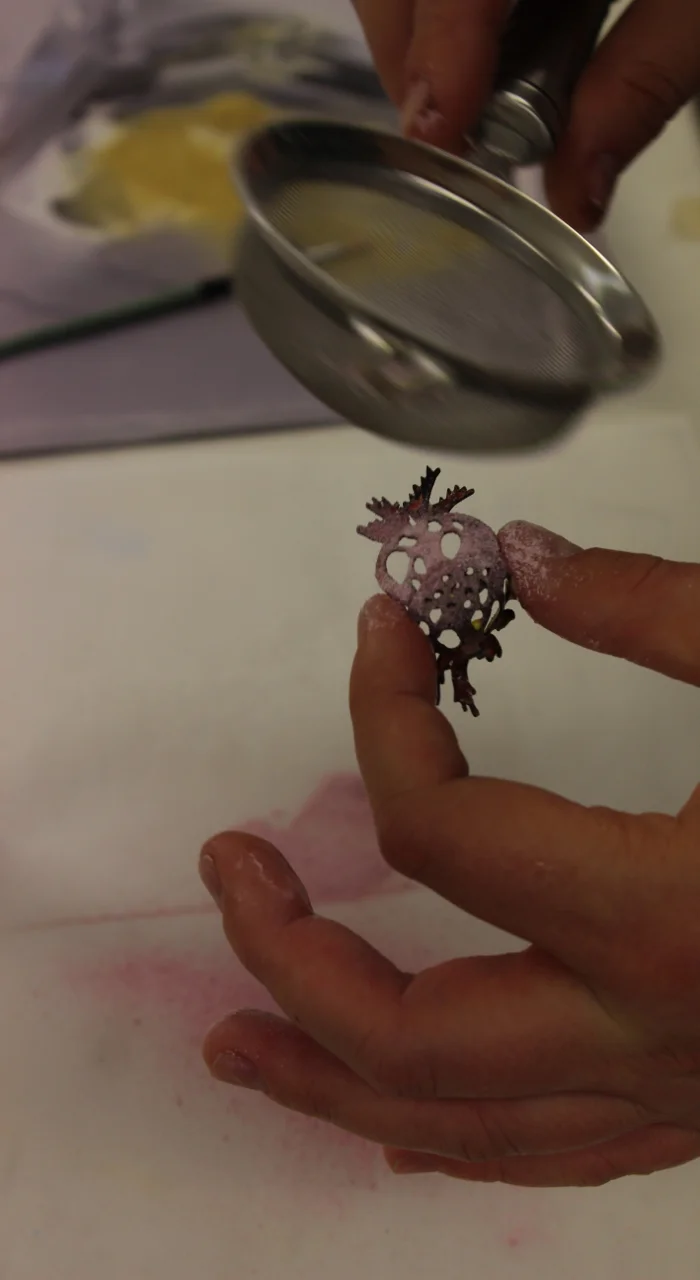 Sifting pink enamel powder onto a copper earring segment.