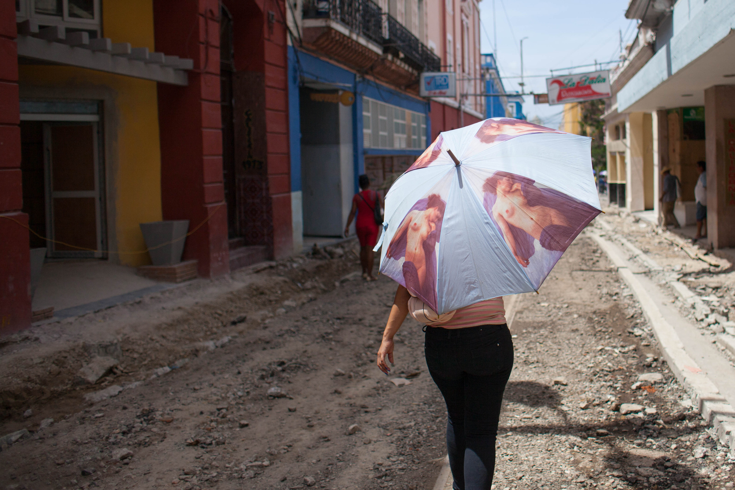  A woman walks down a crumbled street under construction for a walking path in Santiago de Cuba, Cuba. 