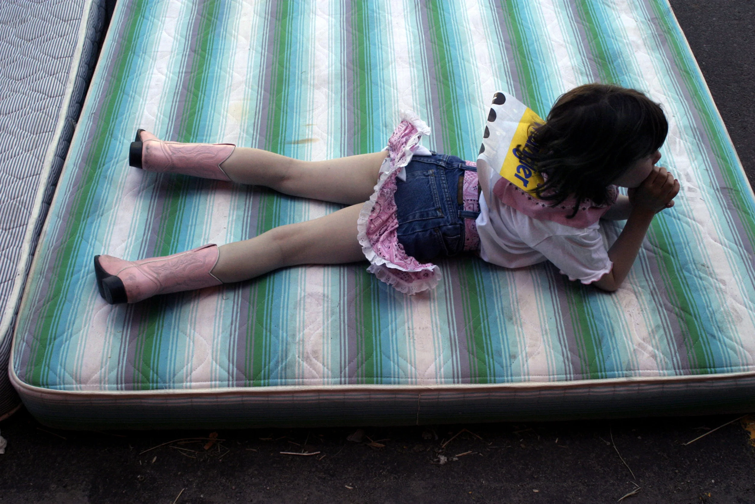 Katie Pronjer, age five, rests on a mattress to protect mechanical bull riding contestants at the Children’s Rodeo in Jackson, Wyo., before placing first in the competition.