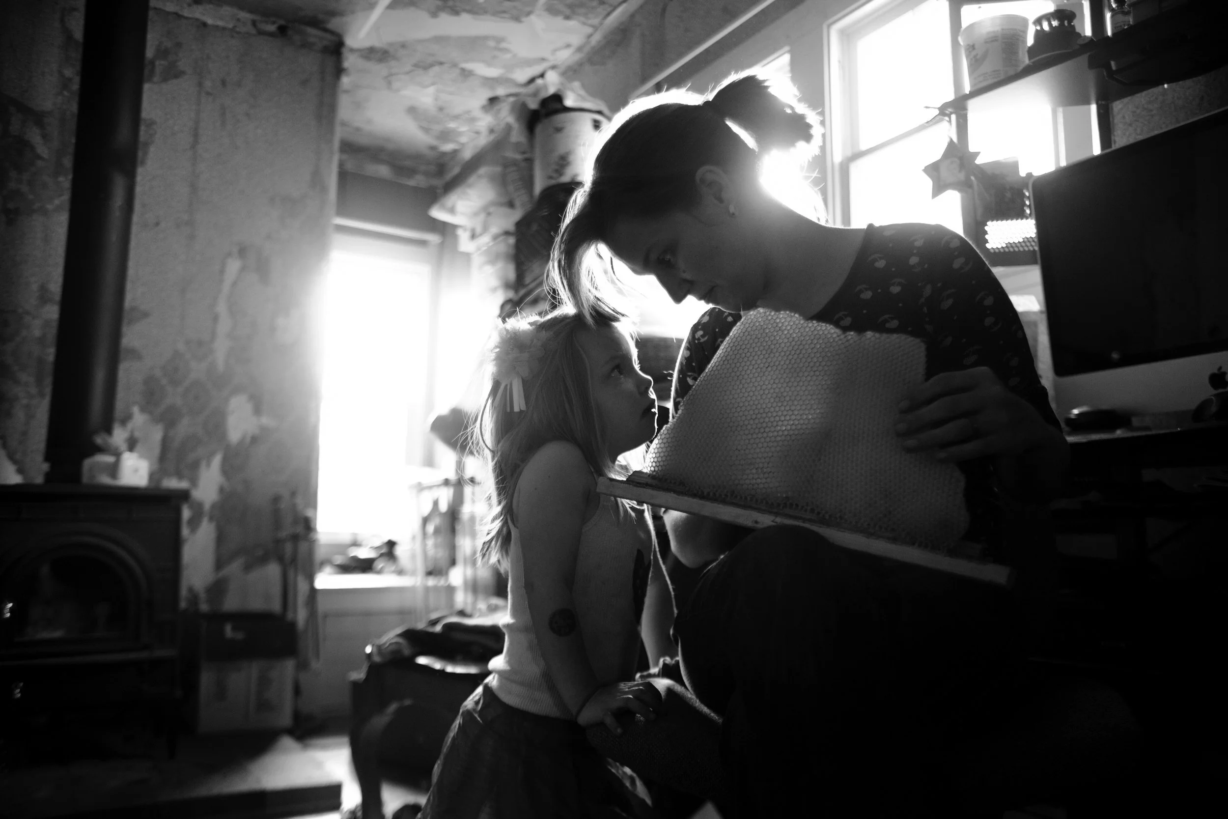 Doroty Deis, age 4, and her mom Jessica look at a honeycomb together after checking on the families' backyard beehive.