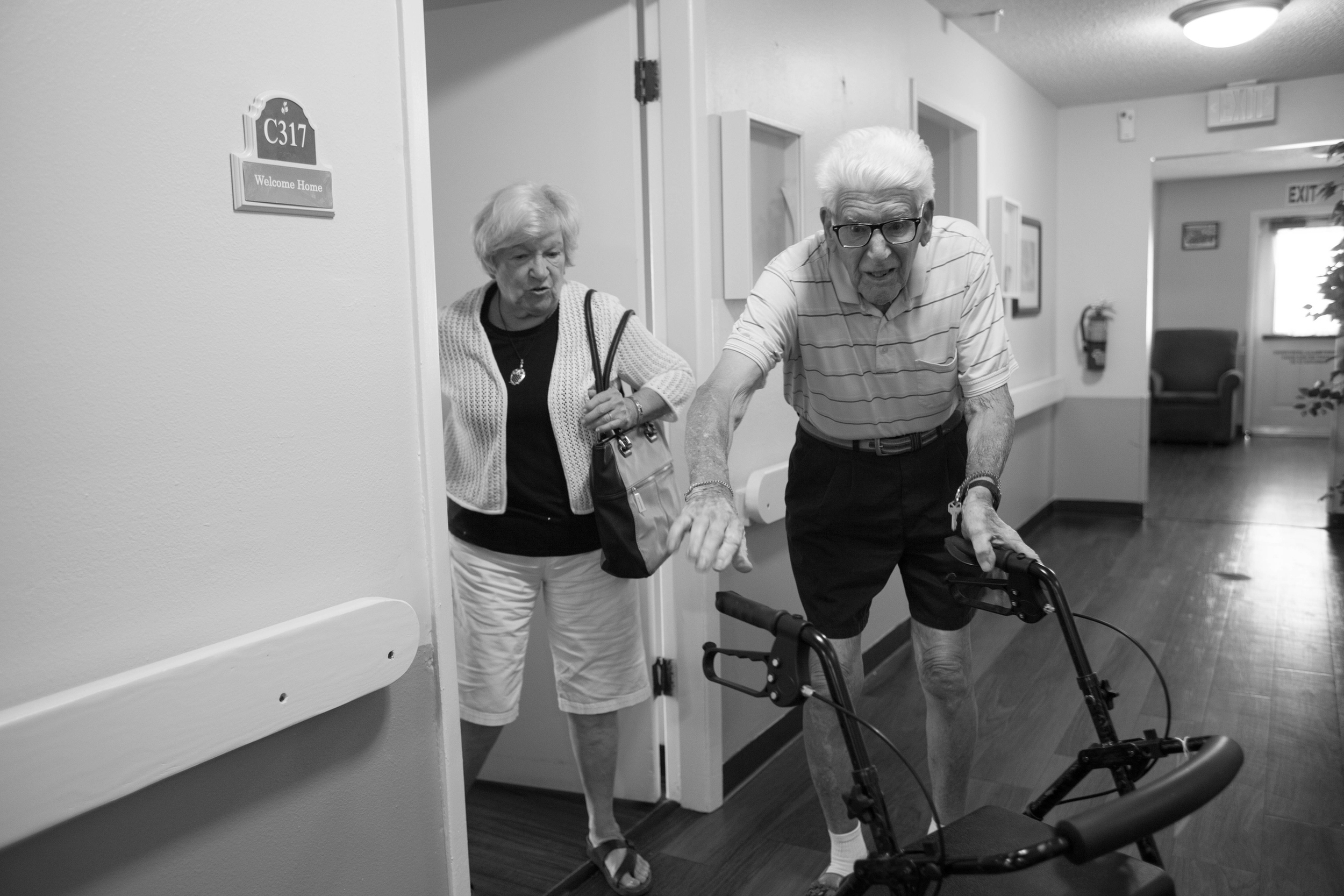 Joye Rush watches as her husband reaches for his walker while heading to the dining hall. "I always told him he could die at home, but I won't live to fulfill that promise," Joye said. 