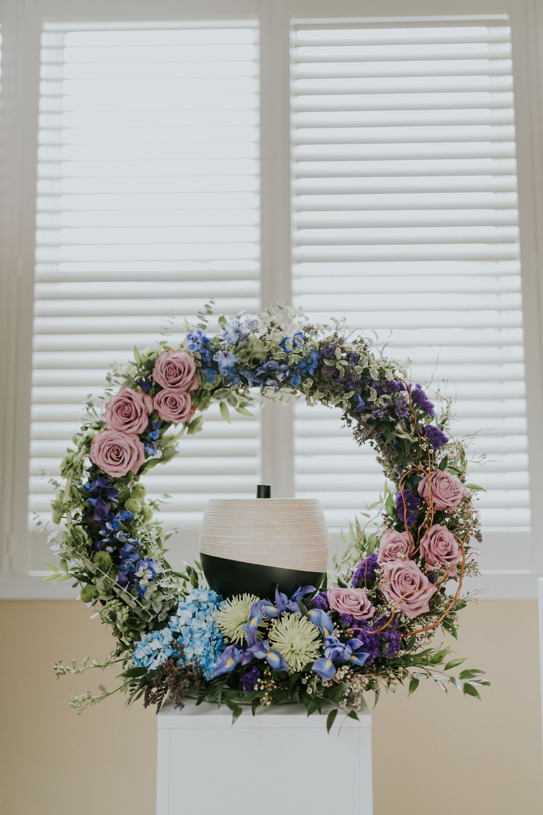  The Tranquil Gate Collection picks up on the soft tones of lavender and green and the bolder tones of royal blue and purple. The color of the blue hydrangea finds a space to tie the soft and bold together. The collection features a casket spray with