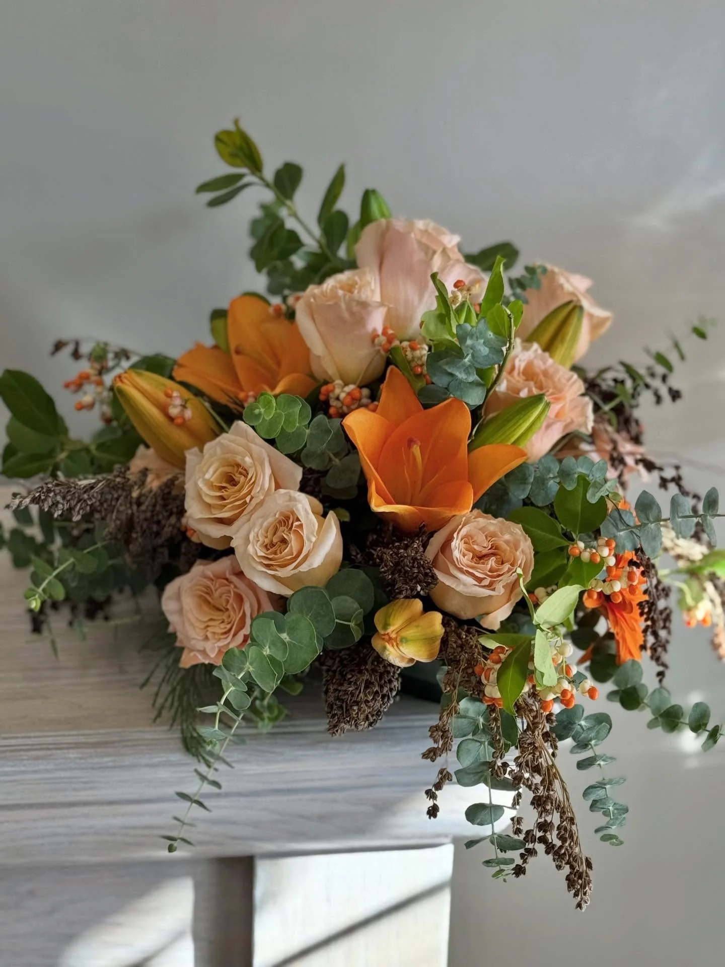 Soft autumn 🍂 Perfect centerpiece for those fall holiday gatherings with the peaches, oranges, and touches of the Michigan outdoors with local eucalyptus, broomcorn, and bittersweet.