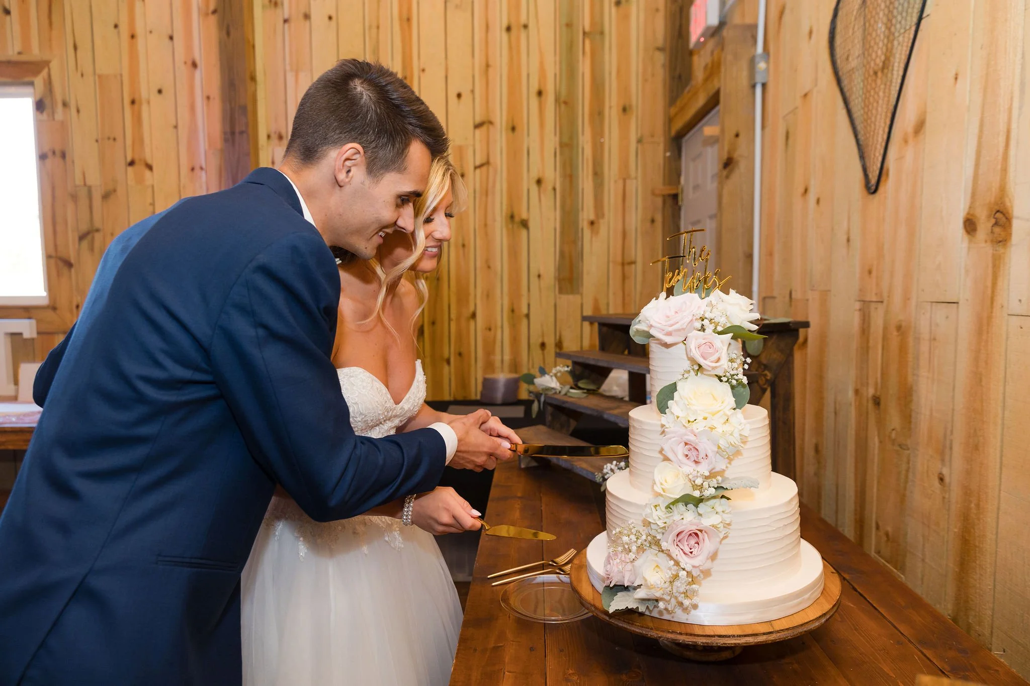 Bride and Groom Cutting a Three Tier Cake with Pink and White Flowers.JPG