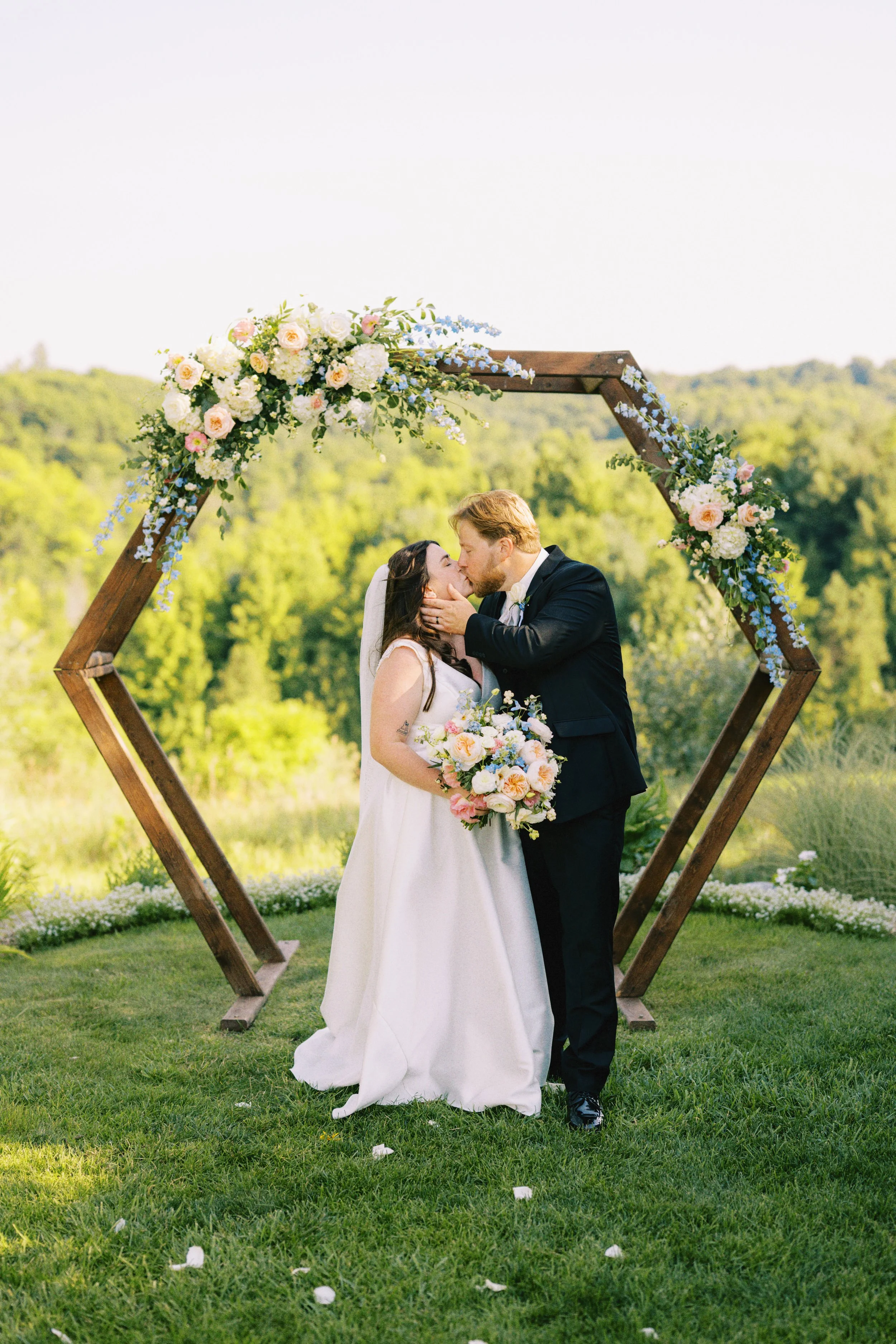 Bride and Groom Kiss under a hexagon arch with flowers by WSFloral at Timberlee Hills, Traverse City, MI.jpg