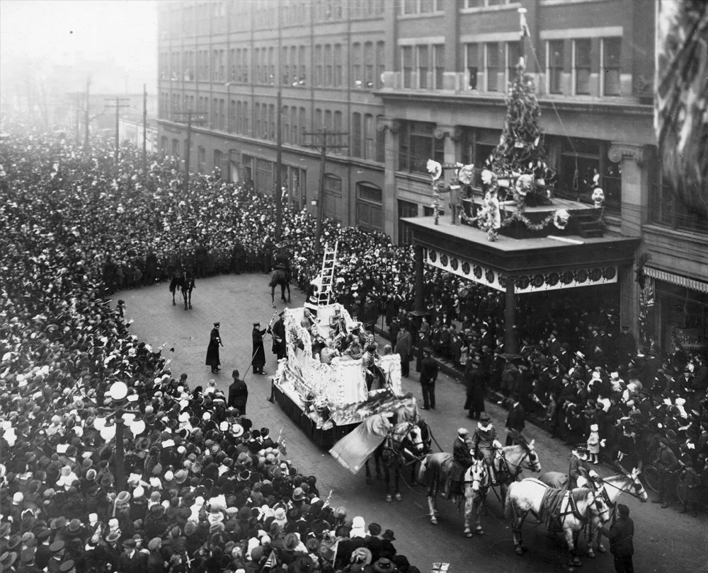Santa climbing the ladder from a float to the Eaton’s department store during the 1918 Eaton's Santa Claus Parade in Toronto.