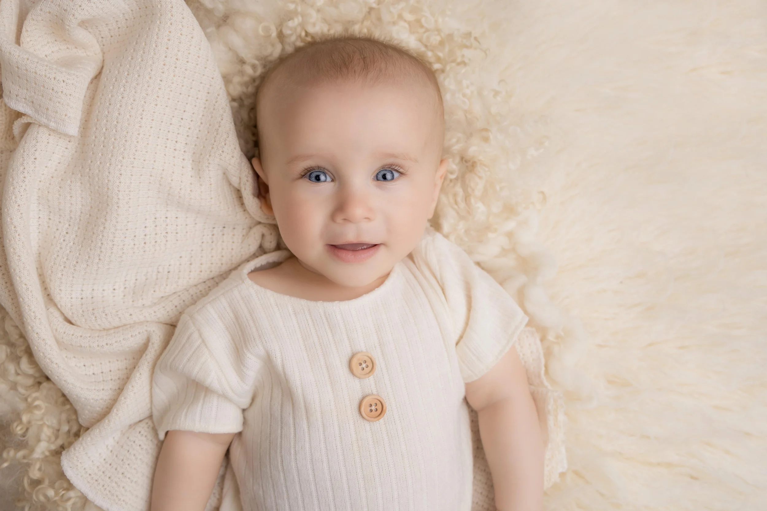 Smiling baby celebrating a new milestone during a professional baby photoshoot.