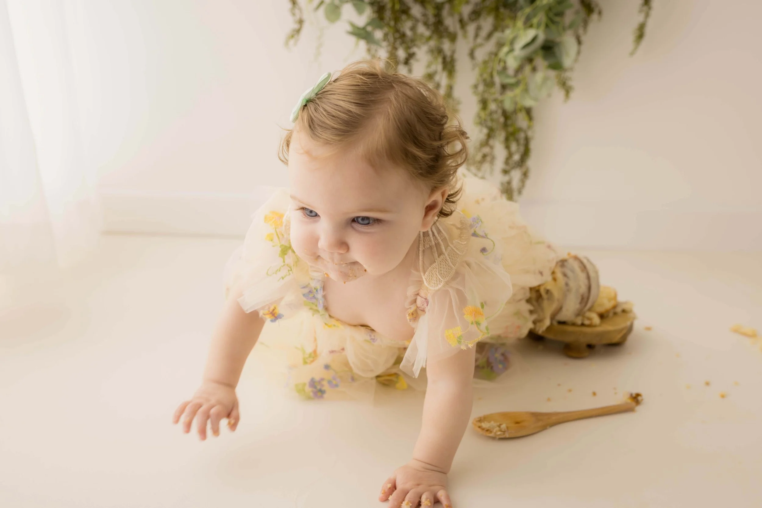 Baby celebrating their first birthday during a professional cake smash session.