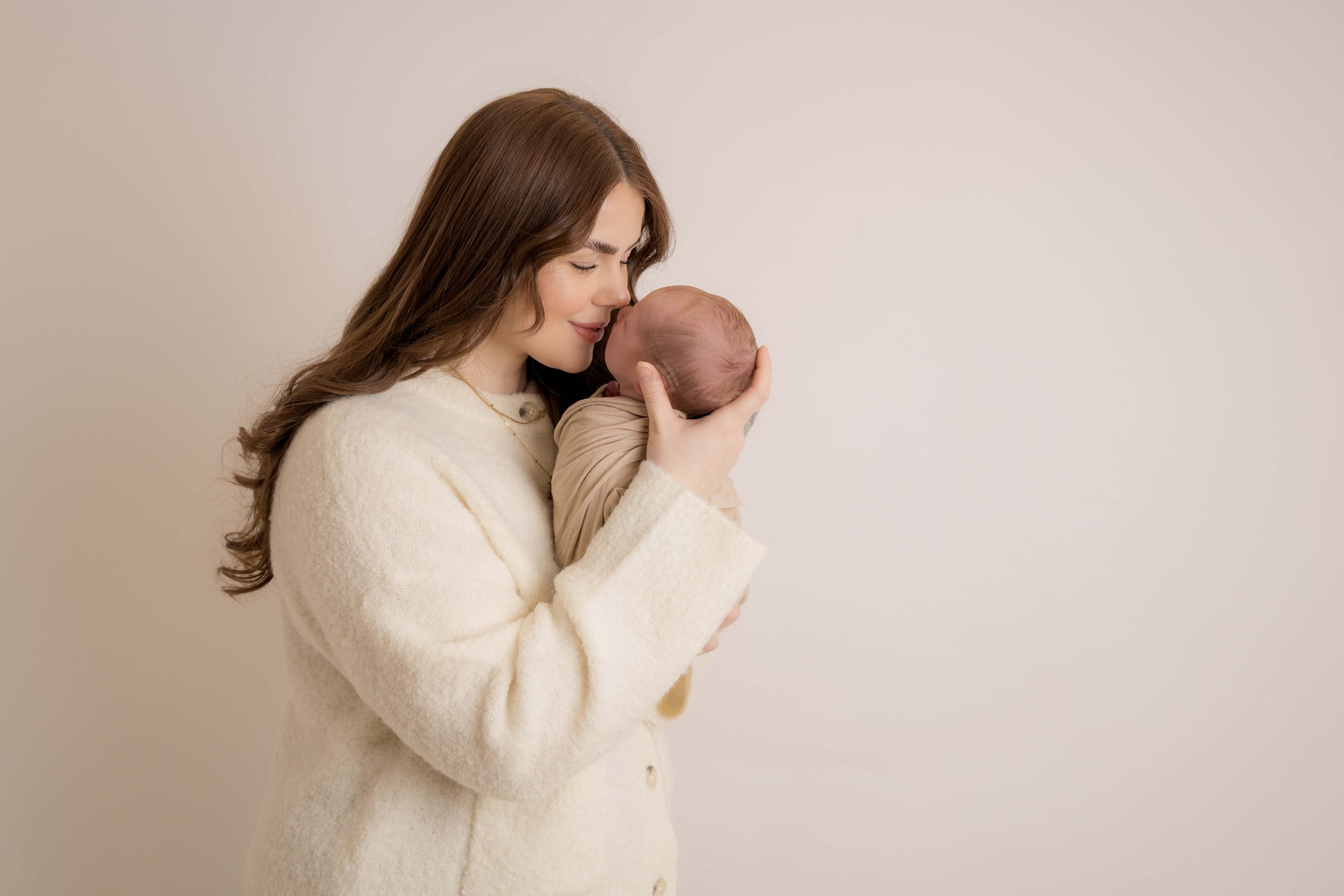 New mum holding her sleeping newborn during a calm, baby-led newborn photoshoot in Bedfordshire.