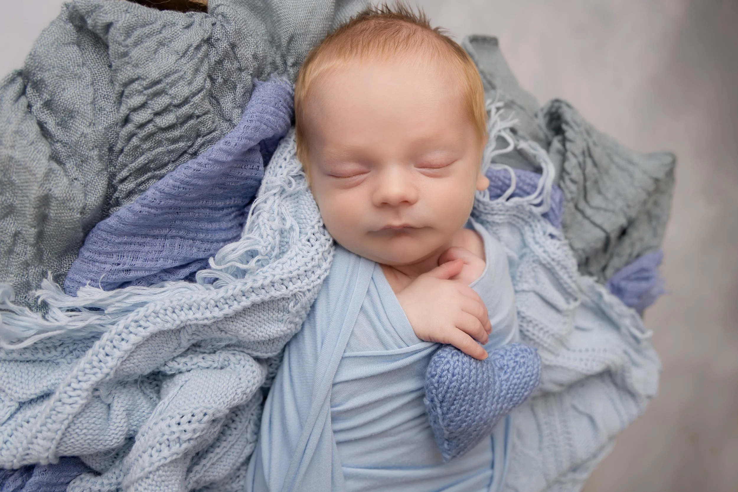 newborn baby boy in beautiful blue wrap at home studio bedfordshire