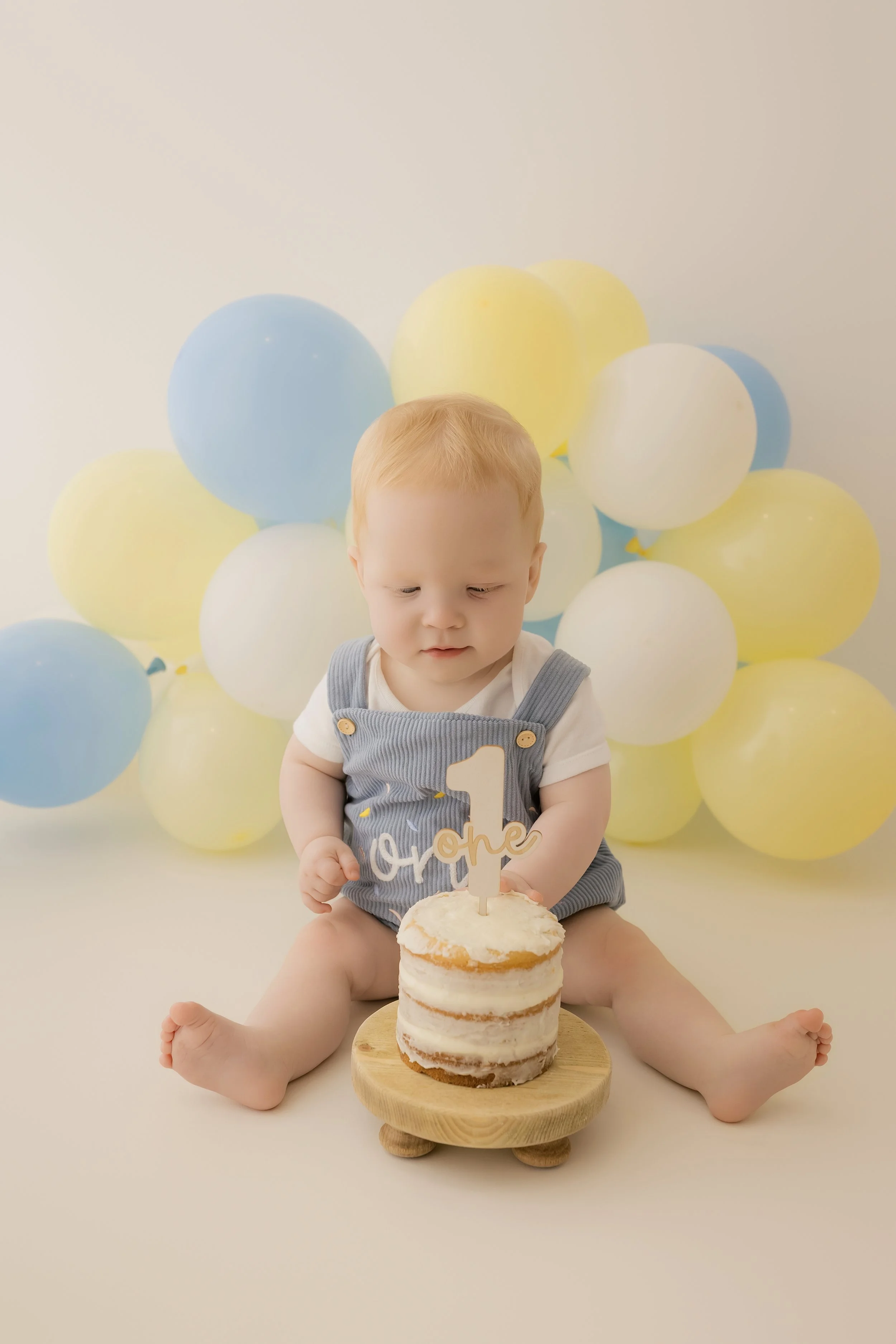 Baby enjoying first birthday cake smash session
