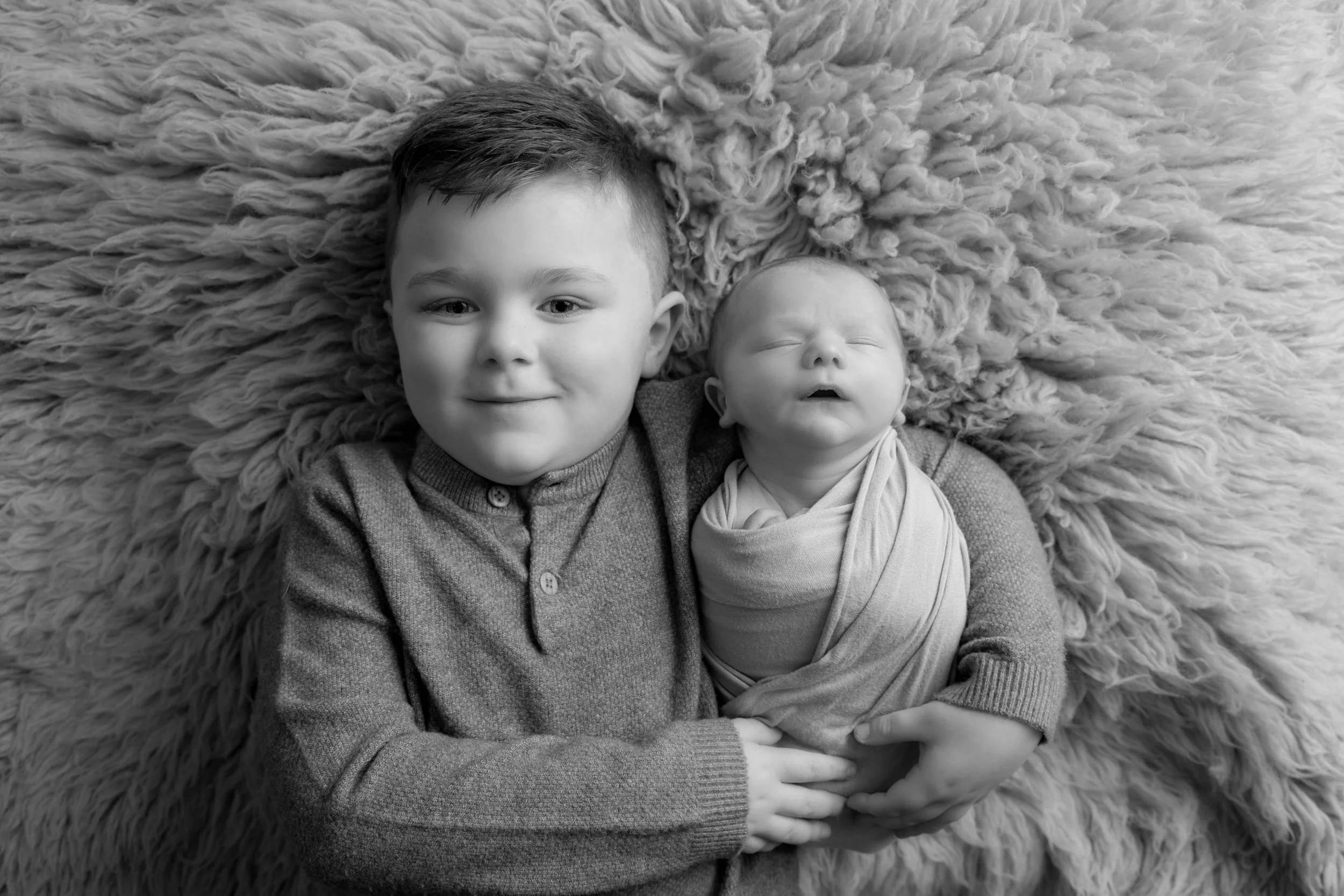 Brother sharing a special moment with his newborn sibling during a relaxed family newborn photoshoot in Bedfordshire.