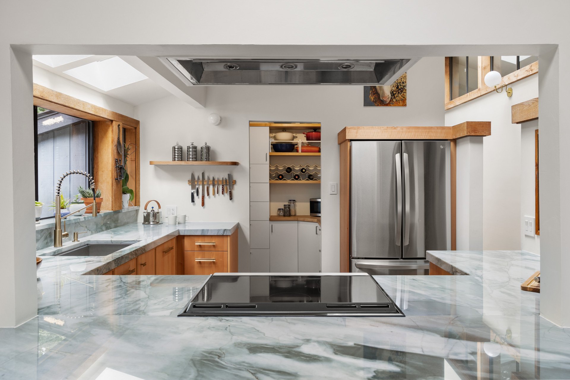 Passthrough into kitchen with swirling green, white, and gray natural stone quartzite countertop.