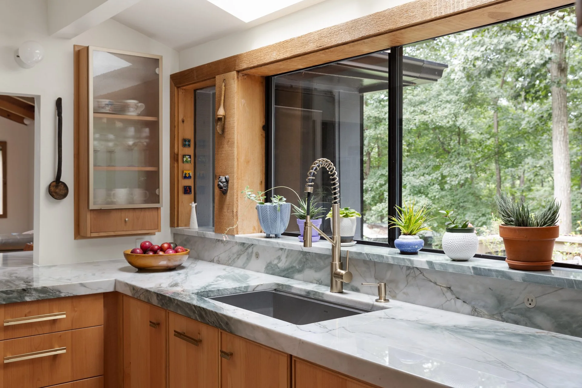 Countertop at a sink and large windows. The countertop backsplash wraps up onto the windowsill as a space for plants.