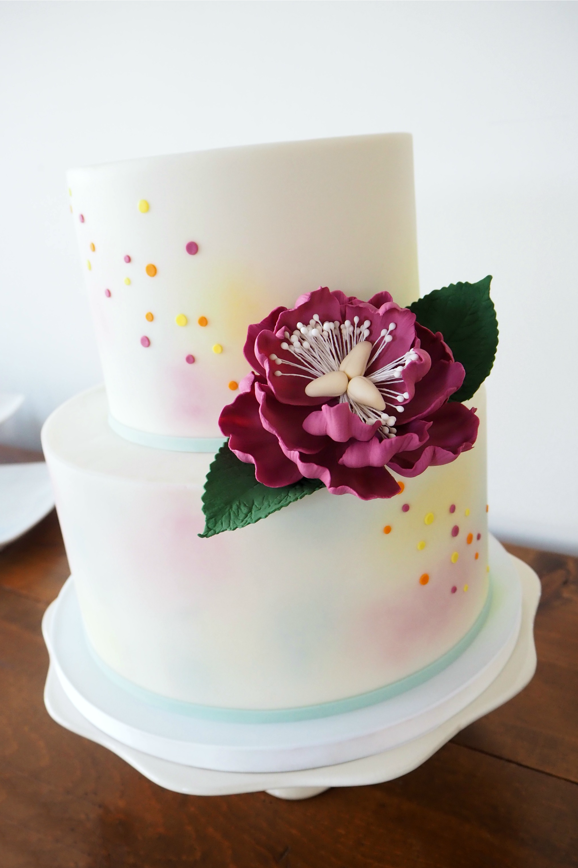 Watercolor and confetti cake design with a striking sugar peony