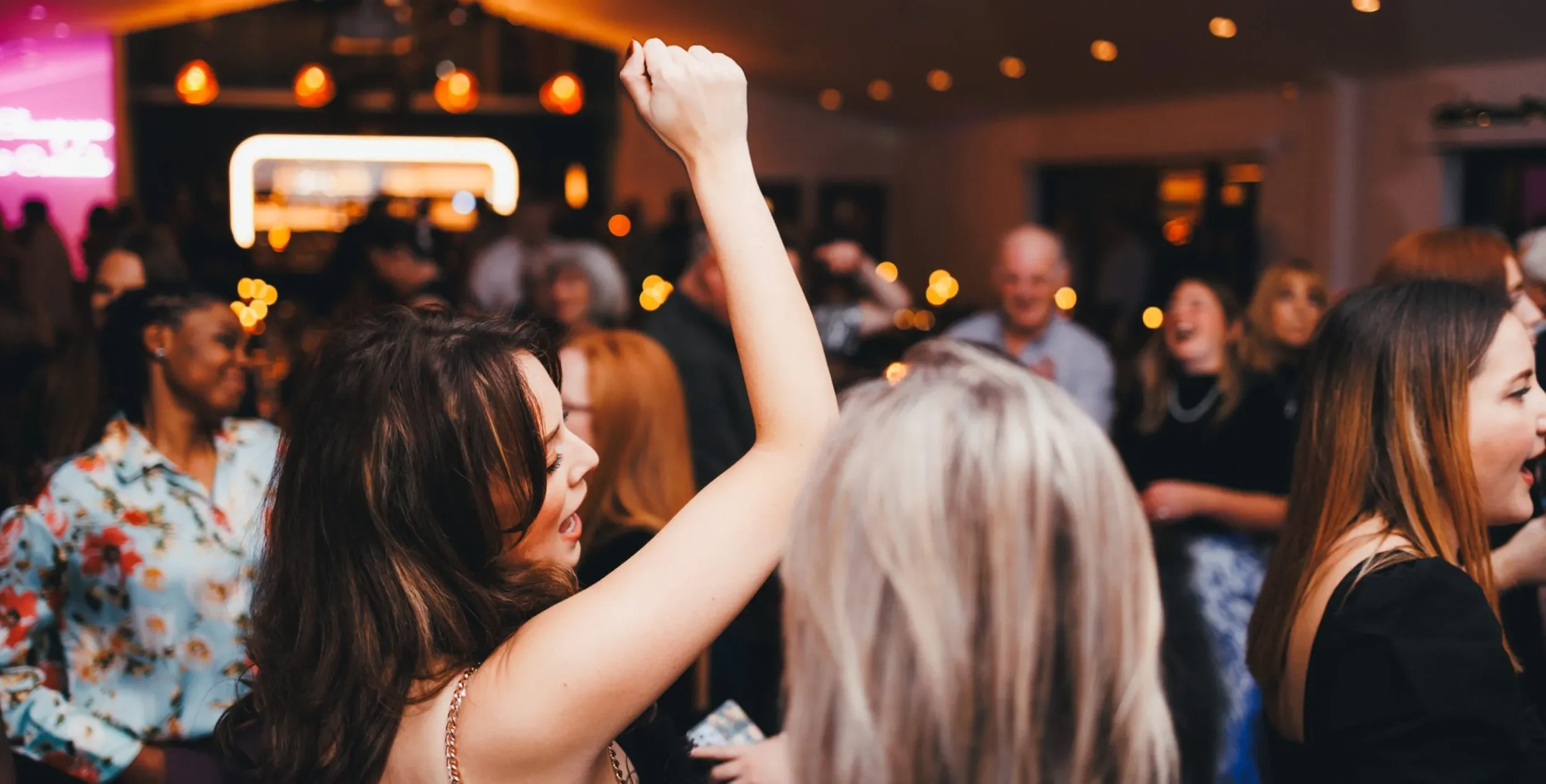 Friends dancing and singing along on the dancefloor during the wedding evening