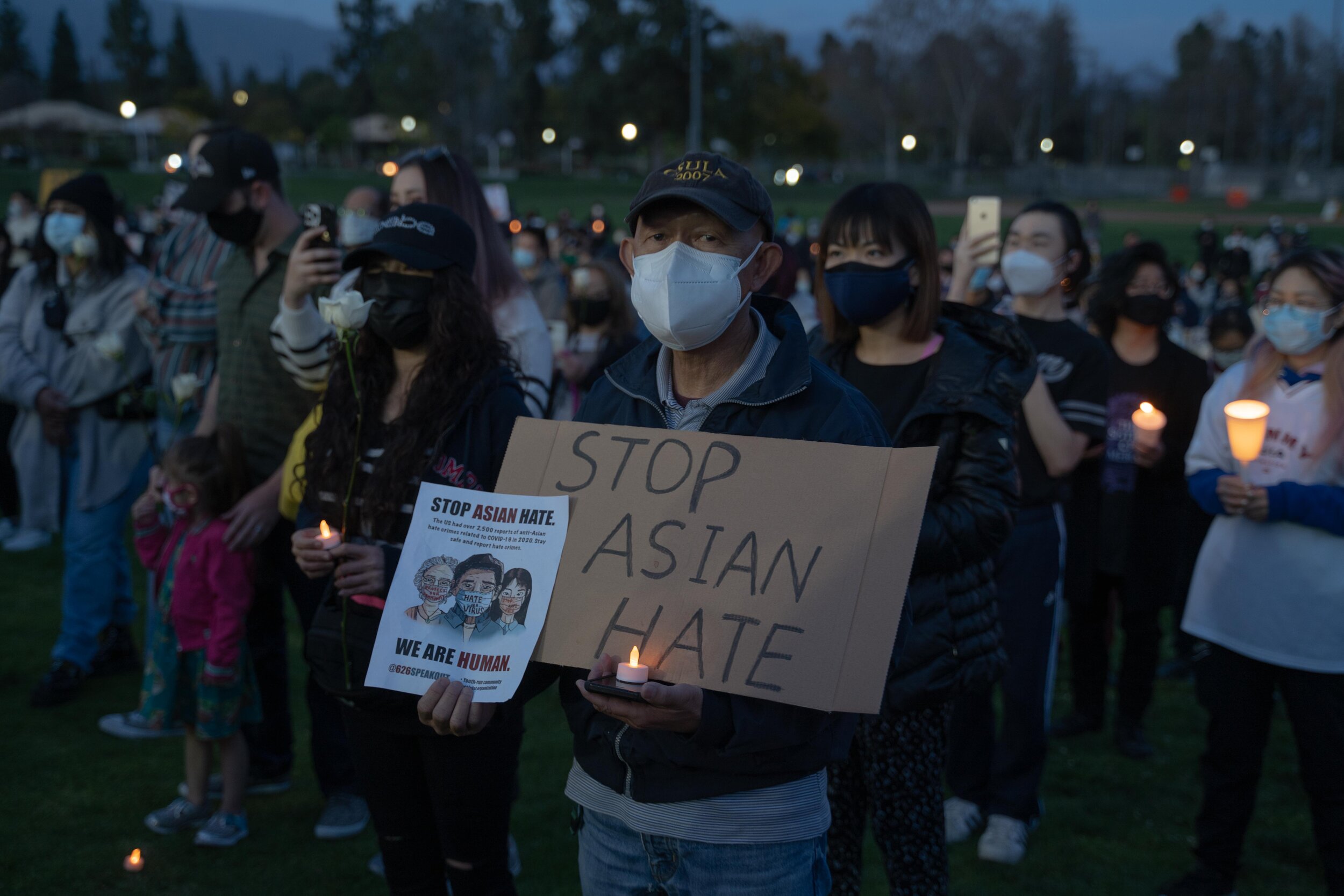 A man holds a sign and candle during a Stop Asian Hate vigil in SGV.