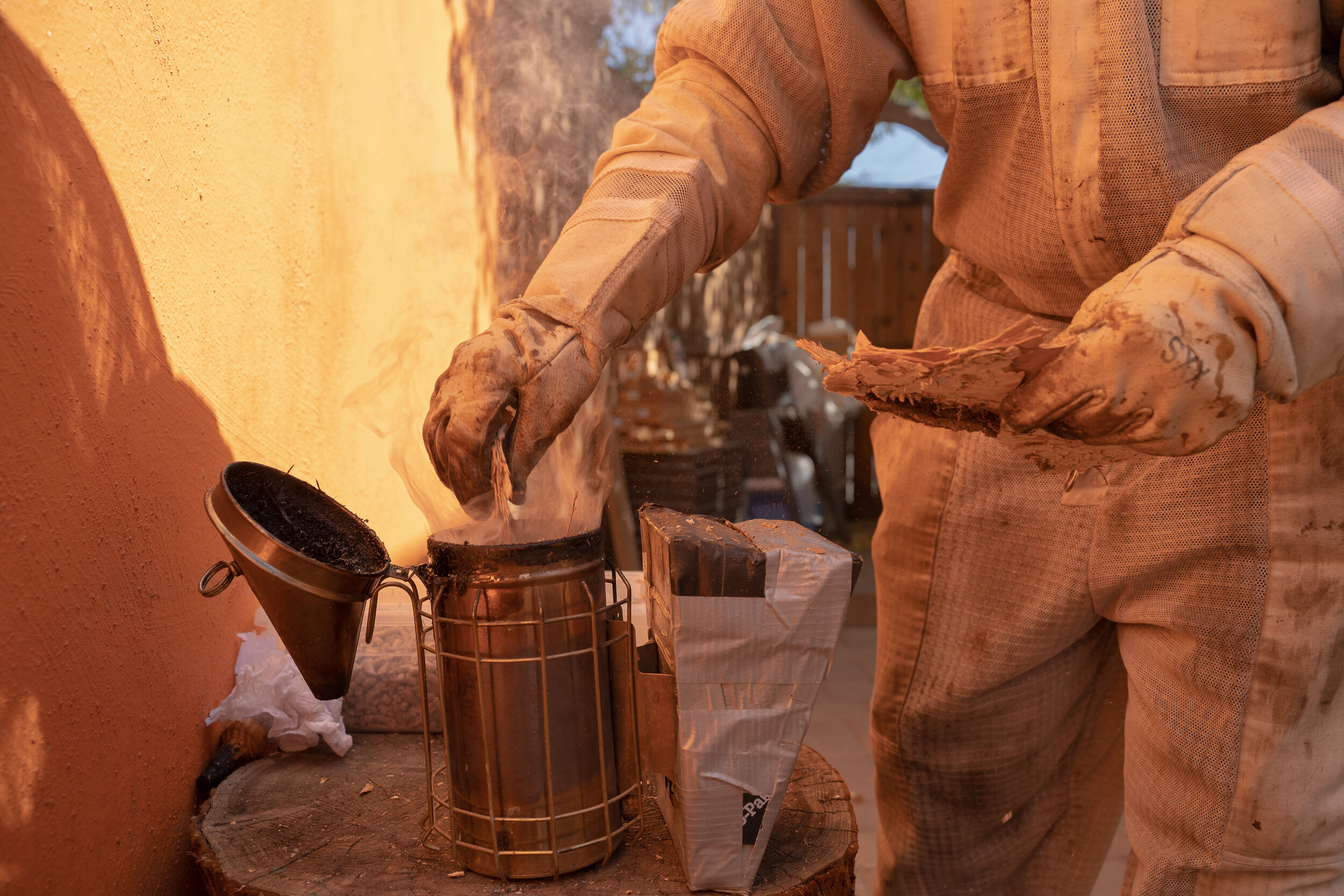 Potter refills her smoker with bark she collects from a nearby tree.