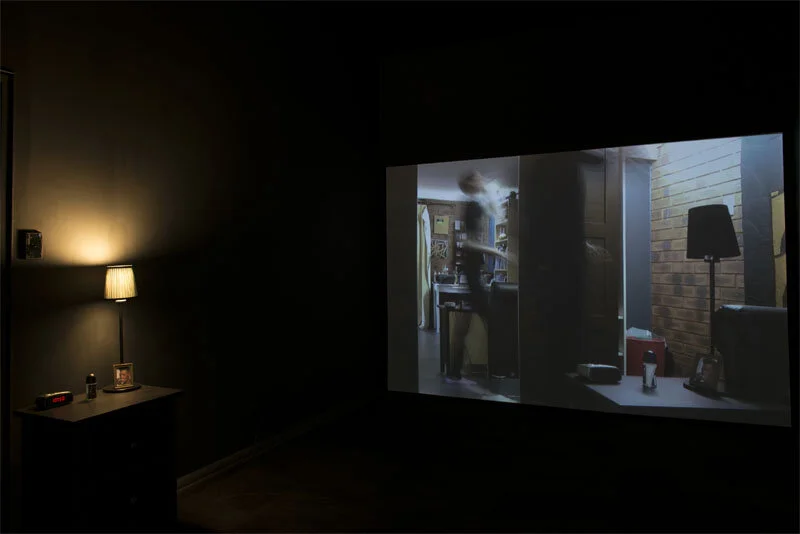 Lill Colgan,  Caught In Reflection , 2014, single-channel video, 49 minutes 28 seconds, artist's bedside table, lamp, alarm clock, and a framed image of Grace Jones, dimensions variable. Courtesy the artist.