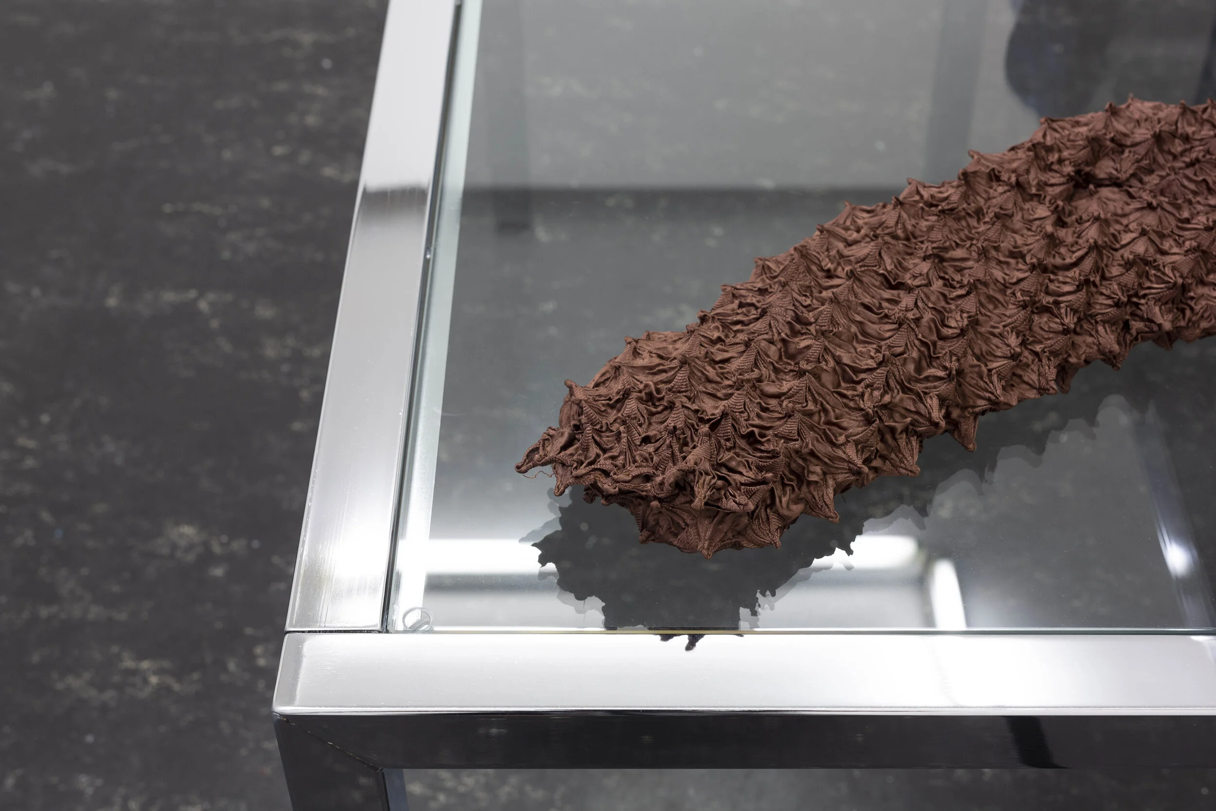 Lill Colgan,  Garment Must Be Handled Delicately, Pulled to Shape, Hand Squeezed , 2020, chrome nesting tables, dressing room hook, second-hand garments, rice, and essential oils, dimensions variable, installation view (detail),  A Hole Where There Once Was A Logo , 2020, Firstdraft, Sydney. Photo: Jessica Maurer. Courtesy the artist.