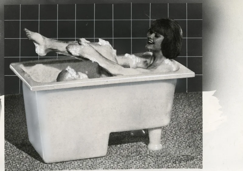 Vrouw badend in schuim in een rechthoekig bad gemaakt van polyetheen, 1964. Woman in bathtube made of polyethene, 1964.