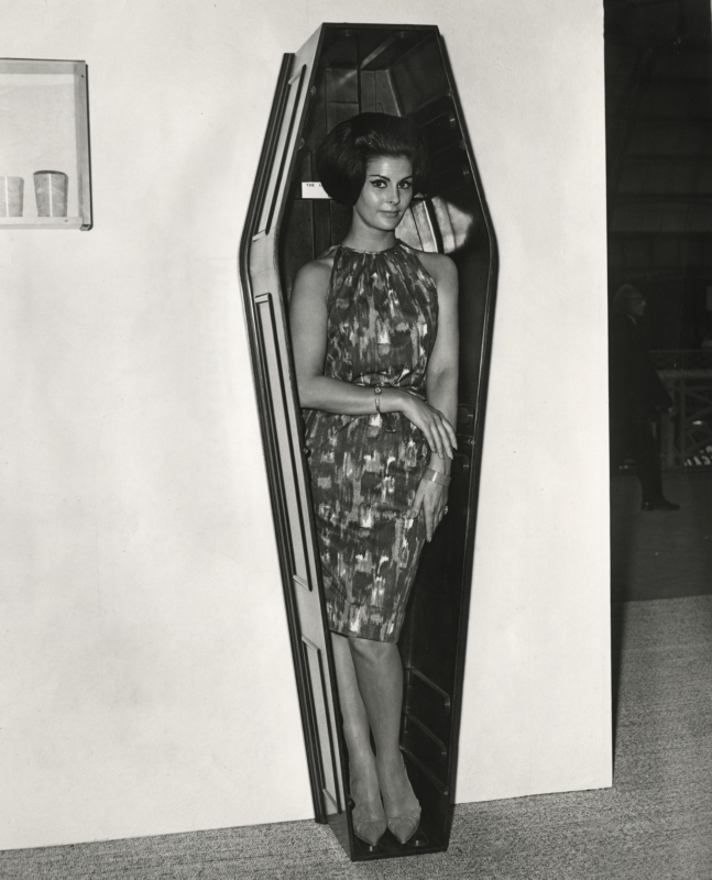 Model Eileen Noble in een doodskist van kunststof, 'The Body' geheten, op de tentoonstelling Interplas 63. Londen, 1963. Model Eileen Noble in a plastic coffin, called ‘The Body’, on an exhibition. London,1963.