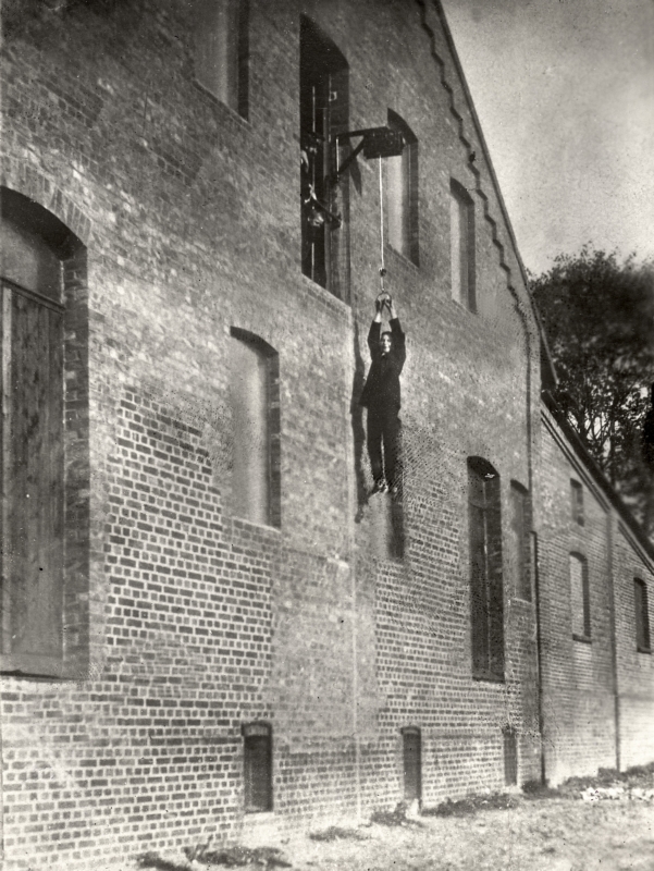 Hier wordt een "patiënt die aan de slaapziekte lijdt" het ziekenhuis in gehesen omdat zijn ledematen niet gebogen mogen worden,1914. ‘A patient suffering from the sleep disease’ is being hoisted into the hospital because it is not allowed to bend his limbs, 1914.