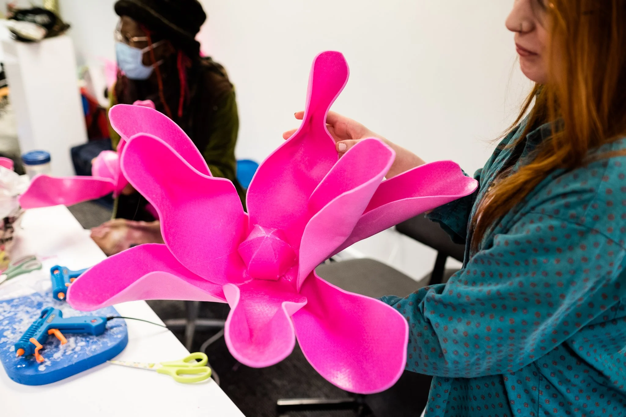 person holding large flower made of pink material