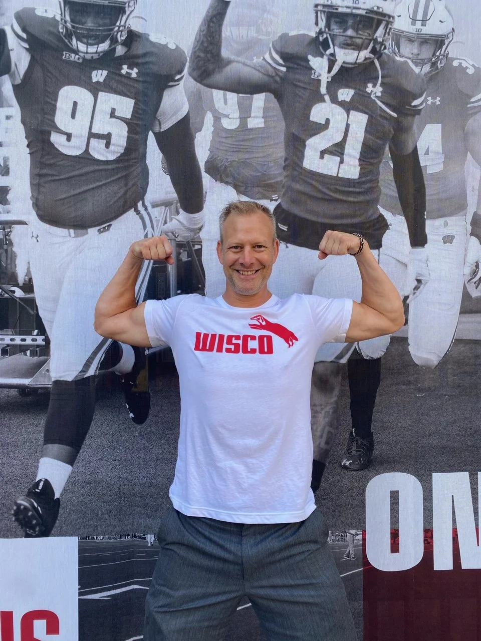 a man wearing a sueded cotton unisex white tshirt with Wisco INTL screen printed graphic featuring Jumping Badger in the Puma style.