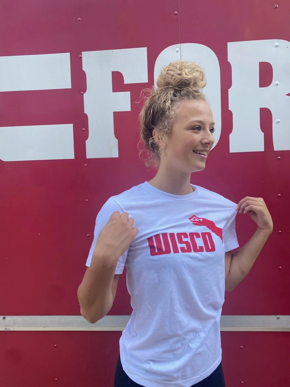 A girl wearing a sueded cotton unisex white tshirt with Wisco INTL screen printed graphic featuring Jumping Badger in the Puma style.