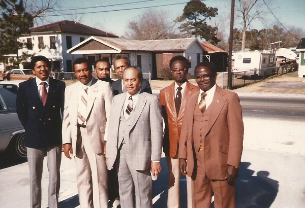 Group of people wearing suits and smiling.
