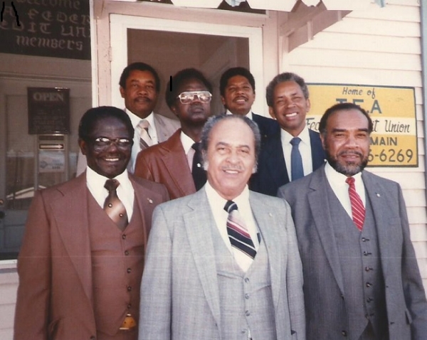 Group of seven people smiling in front of the first T.E.A. FCU location.