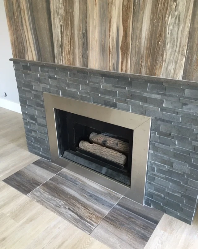 Grey brick facade fireplace design in Huntington Beach with natural wood on top - right angle shot