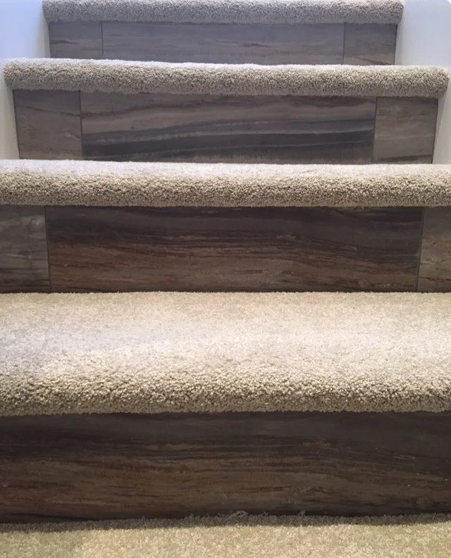 Straight on shot of beige designer staircase with carpeting and wood