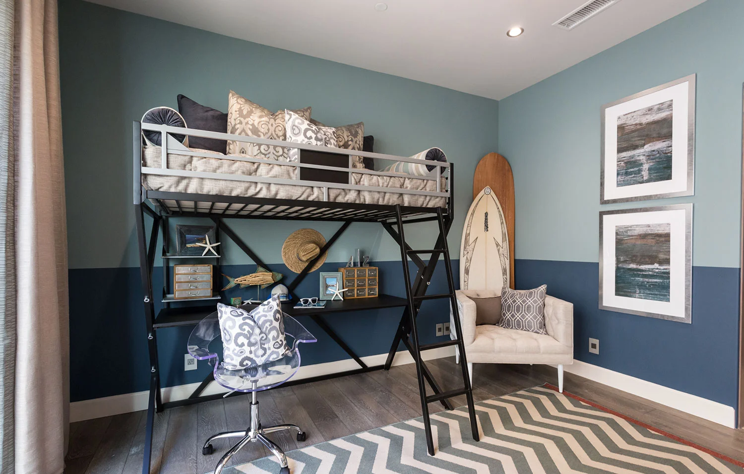 Blue teen boy bedroom design with wooden floors, patterned area rug, and lofted bed with workspace beneath