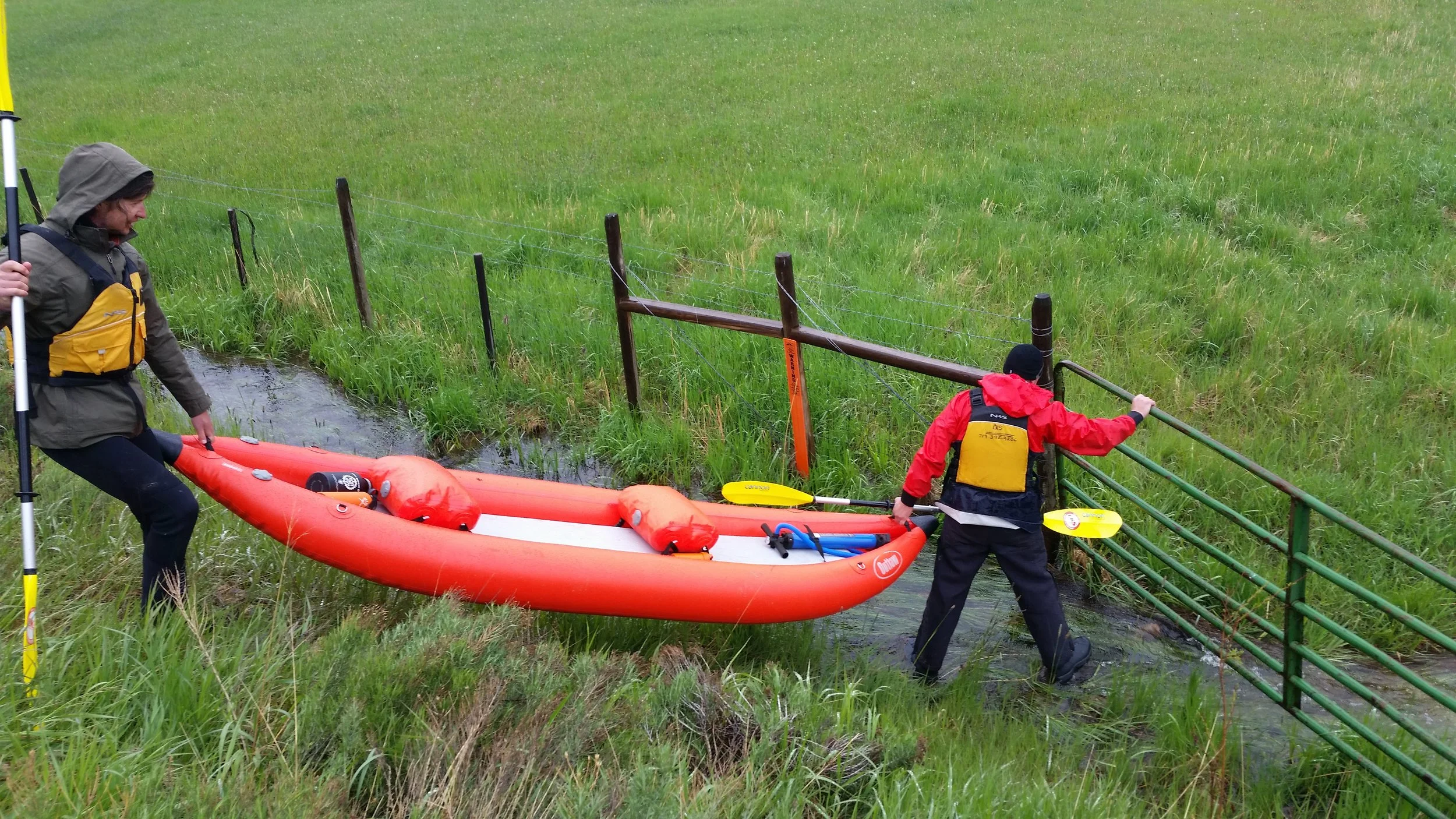  Lincoln and John load an inflatable kayak over a barbed-wire fence, shortly before loading into the Little Snake River in southern Wyoming. [Photo: Damien Willis]   