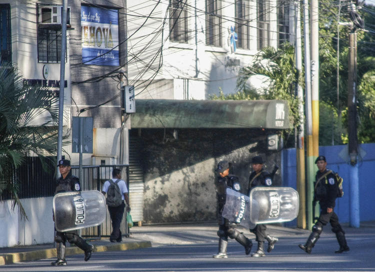 Riot police walk in front of the 100% Noticias cable and internet news station in Managua on December 22, 2018, a day after the station was raided and closed by the Nicaraguan police. Two journalists were arrested during the raid. [Photo: AFP/Maynor…