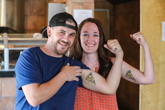 Wade and Jamie McDonald show off their matching pizza tattoos while at King Zah's Pizzeria on Thursday, May 14, 2020. The two met while working at Zeffiro's New York Pizzeria on University. Wade purchased the space and plans to open King Zah's soon.…