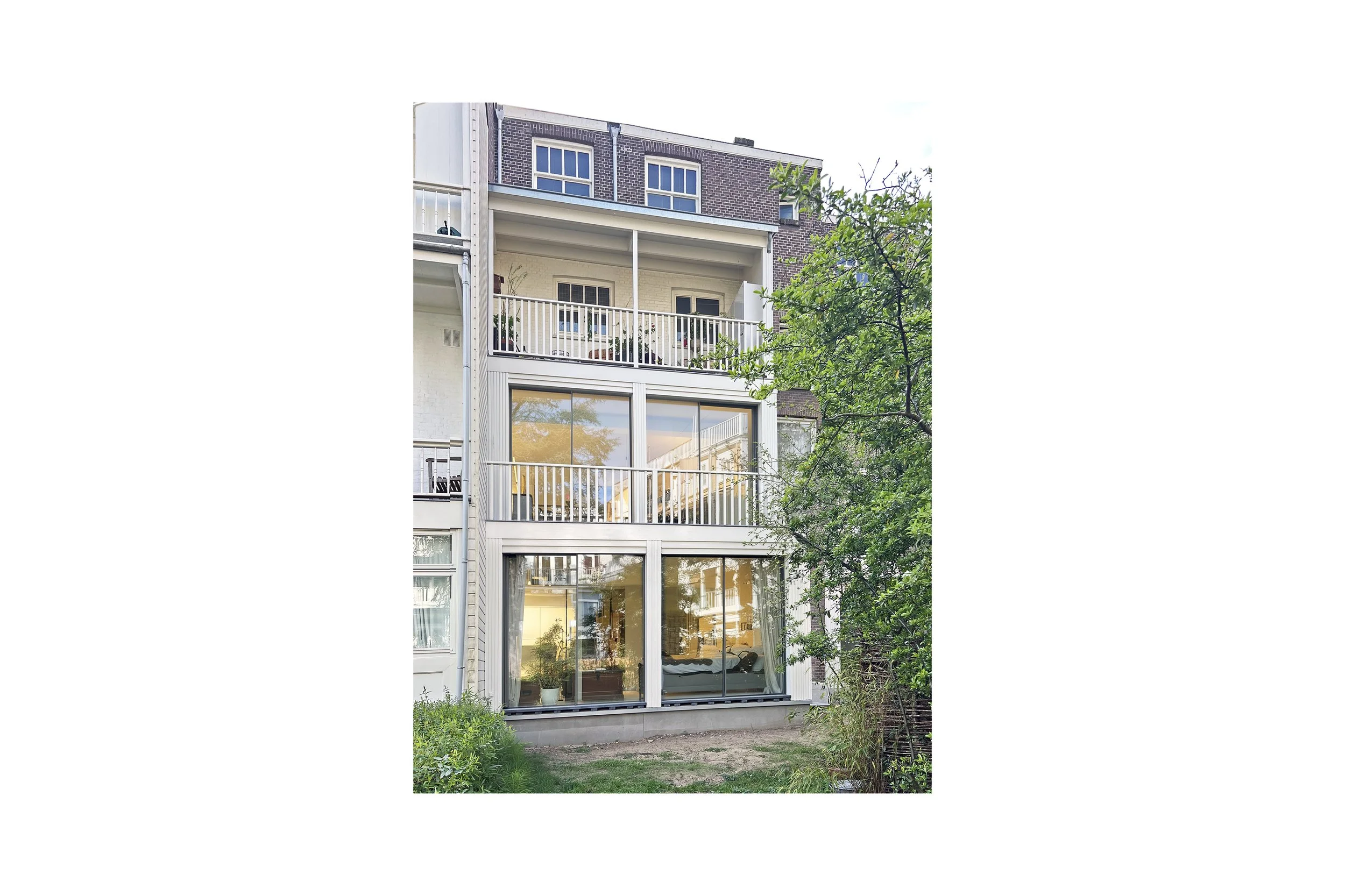 Multi-story residential building with large glass sliding doors and balconies, surrounded by greenery.