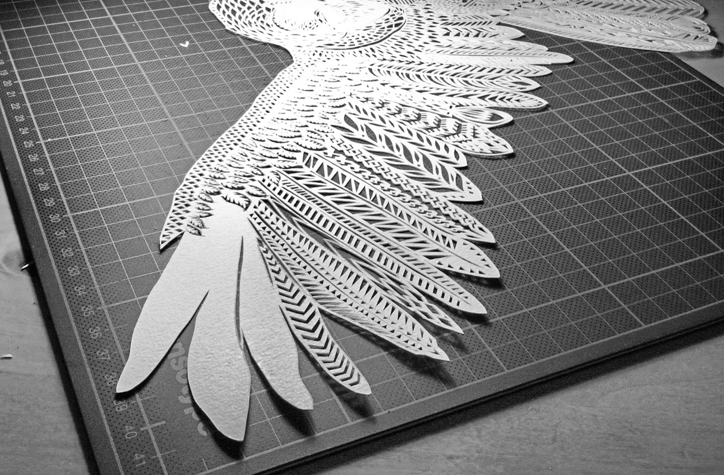 Papercutout of an owl, feathers lifting off the cuttingboard by Thysart