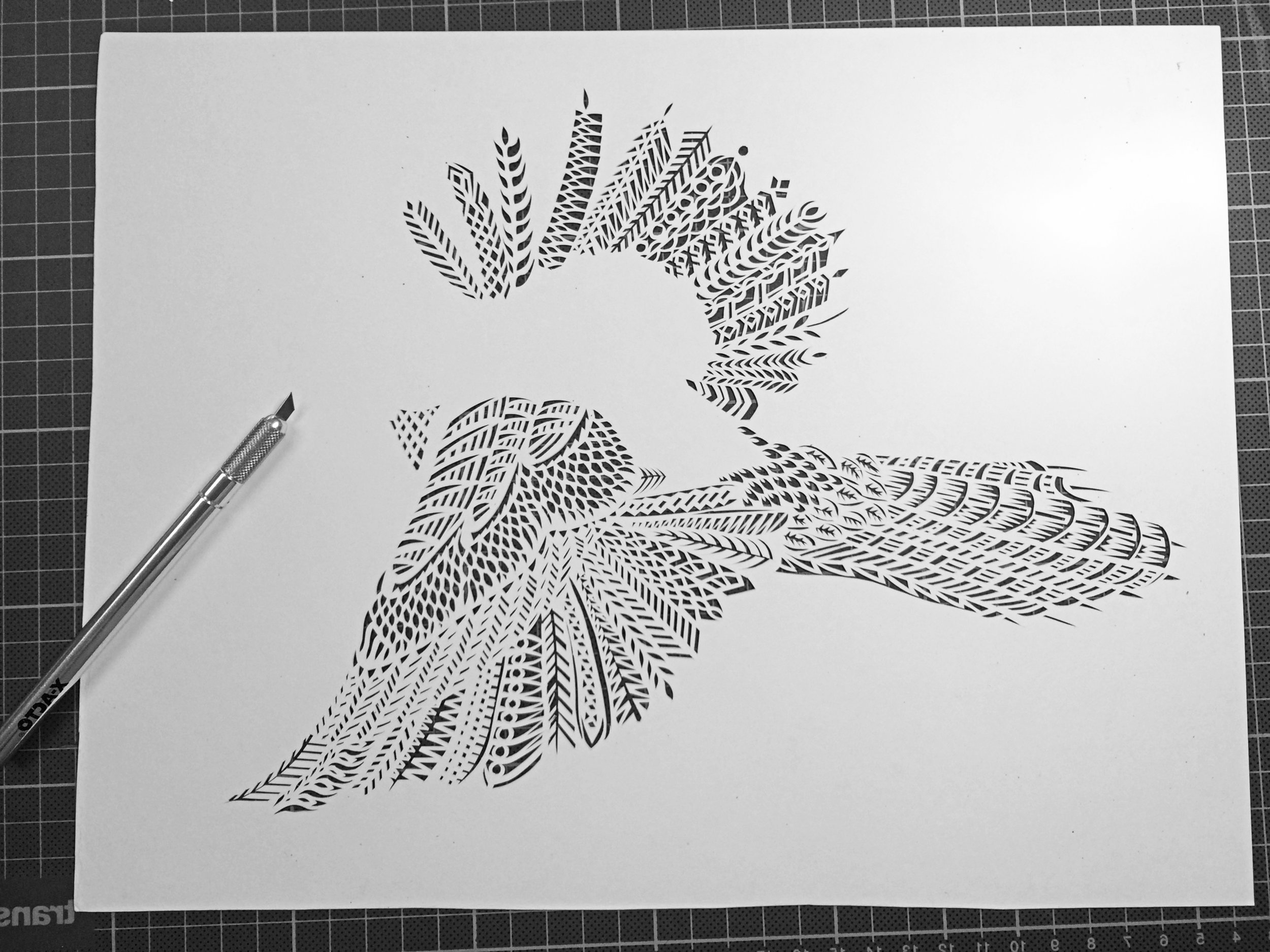 A behind the scenes look into Thysart's studio, a half finished papercutting of a bluejay
