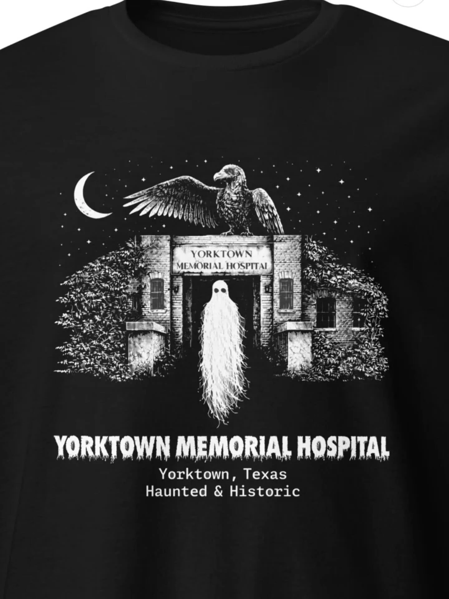 Meet your new favorite T-shirt, featuring the haunting imagery of the legendary Yorktown Memorial Hospital. This design showcases the eerie silhouette of a ghost emerging from the hospital entrance, watched over by a perched vulture beneath a crescen