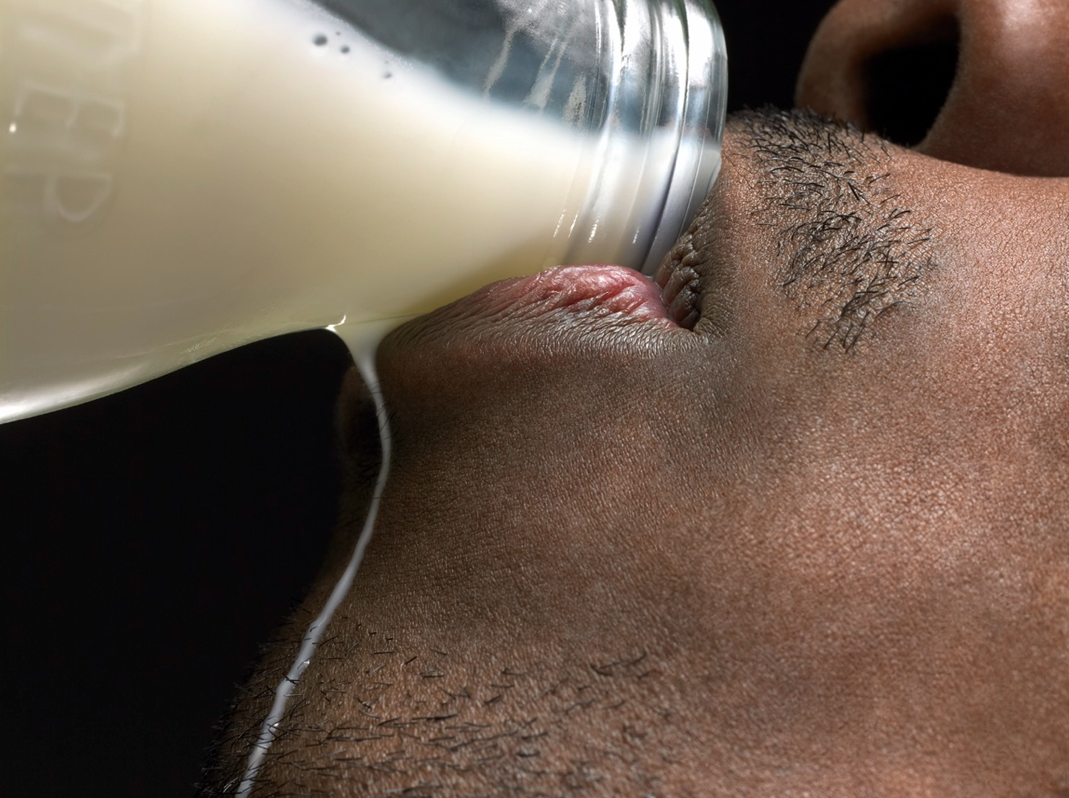 Close-up of a person with facial hair drinking milk from a glass.