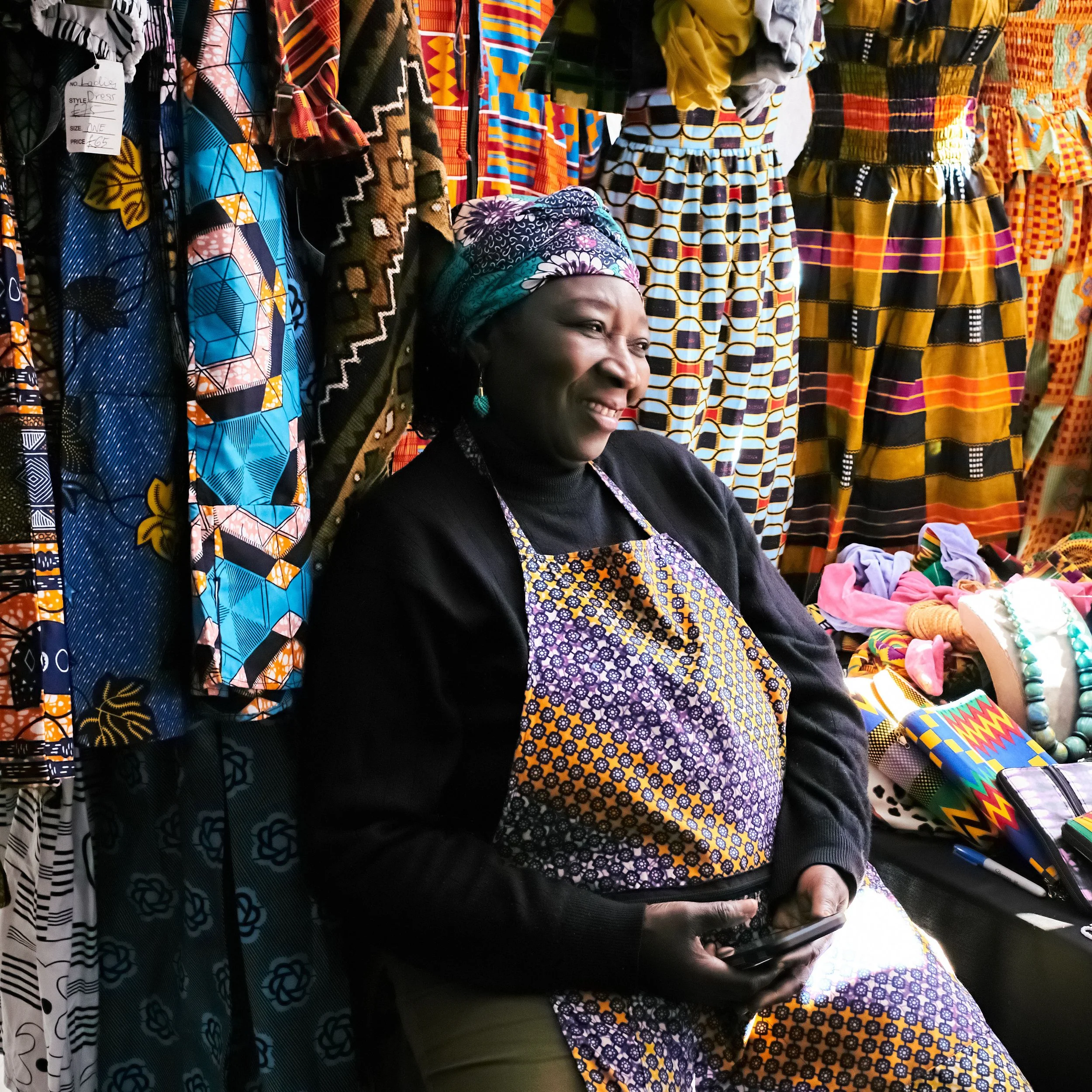 Street portrait of woman surrounded by colourful textiles