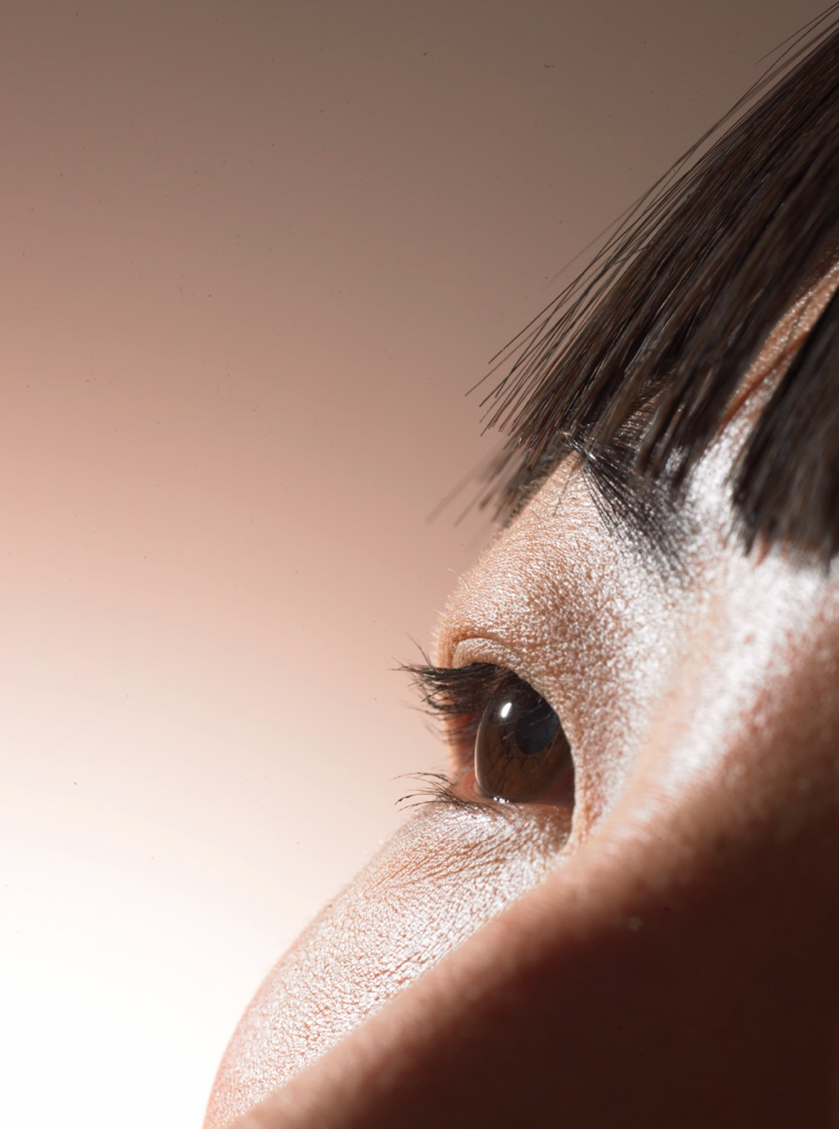 Close-up of a person's eye with makeup, possibly powder or foundation, on the eyelid and surrounding skin, with dark eye makeup and long eyelashes.