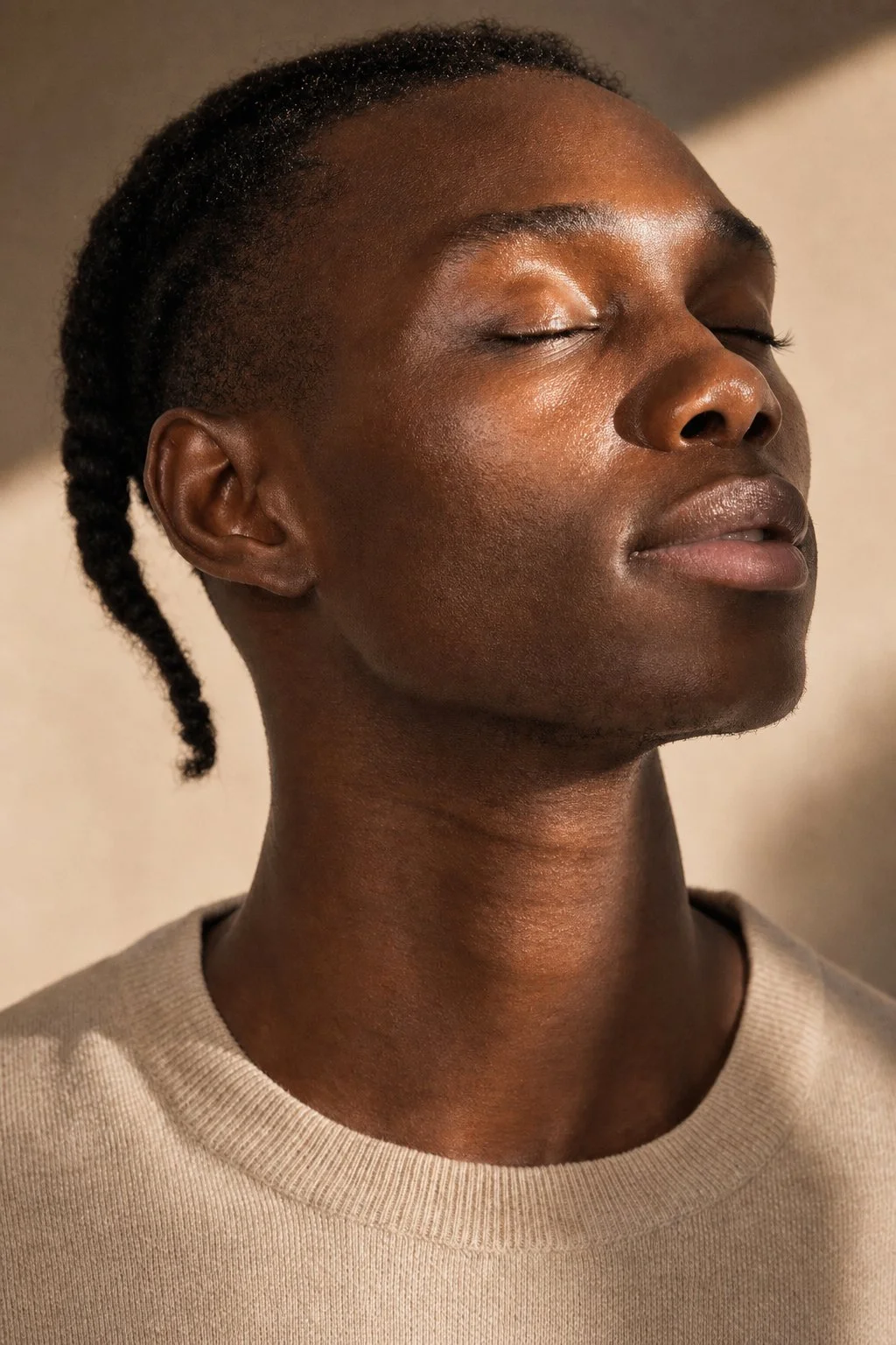Close-up of a person with dark skin and short, twisted hair, eyes closed, appearing calm and relaxed.